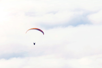 Paraglider flies on the background of clouds on a sunny day/ copy space