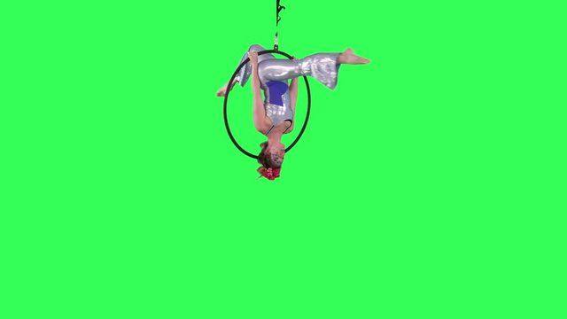 Professional Aerial Hoop Artist spins and performs wearing a circus suit over a green screen.