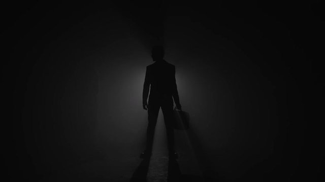 Silhouette of corrupted businessman exchanging briefcase with handshake
