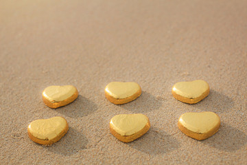 Chocolate color Lovely golden heart on the beach. Background is a natural in real place, creative Valentine's Day Concept, tropical style background made in Phuket, Thailand.