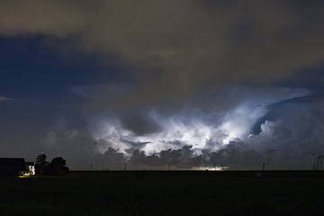 Obraz na płótnie Canvas An autumn thunderstorm over the dutch countryside. The anvil of the storm is clearly visible while illuminated by lightning. 