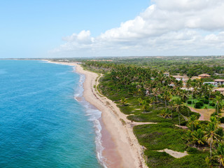 Aerial view of tropical white sand beach and turquoise clear sea water with small waves and palm trees background. Praia do Forte, Bahia, Brazil. Travel tropical concept