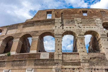 Naklejka premium Facade of the Great Roman Colosseum (Coliseum, Colosseo), also known as the Flavian Amphitheatre. Famous world landmark. Scenic urban landscape.