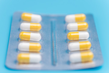Medicine white and yellow pills packed in blisters on blue background