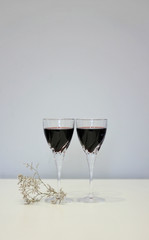 Tender composition - two glasses of red wine on the table and a dry sprig