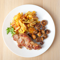 steak with fried potatoes and mushrooms top view