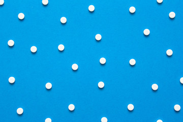Chaotically scattered white pills on a blue background pattern. White pills background. Texture for design.