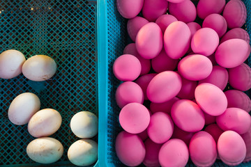 Some white eggs and many pink eggs. They lie in blue baskets. No one needs easter eggs