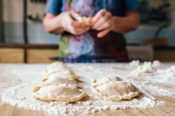 Aged woman preparing cookies filled with cottage cheese. Homemade bakery, traditional cuisine.