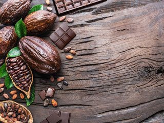 Cocoa pod, cocoa beans and chocolate on the wooden table. Top view.