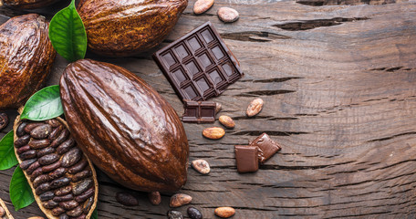 Cocoa pod, cocoa beans and chocolate on the wooden table. Top view.