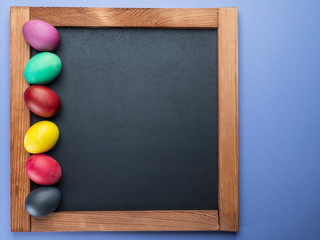 Blackboard and colorful Easter eggs around it. View from above.