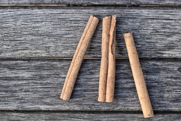 Three sticks of cinnamon lie on the background of old boards - 252916003