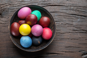 Colorful Easter eggs in bowl on wooden table. Attribute of Easter celebration.