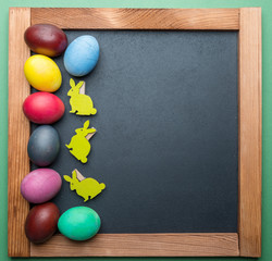 Blackboard and colorful Easter eggs on it. View from above.