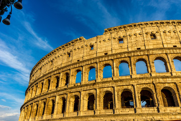 Fototapeta premium Golden sunset at the Great Roman Colosseum (Coliseum, Colosseo), also known as the Flavian Amphitheatre. Famous world landmark. Scenic urban landscape.