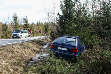 A car destroyed during the traffic accident. The car is abandoned and stands by the road in the trees. 
