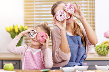 Little girl and her mom in aprons having fun in the kitchen