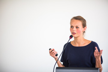 Pretty, young business woman giving a presentation in a conference/meeting setting (shallow DOF;...