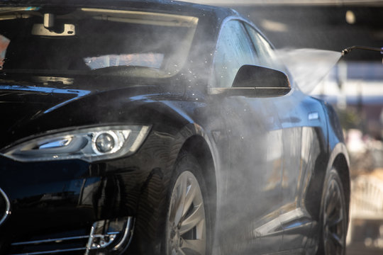 Woman washing her car in a manual carwash (color toned image)