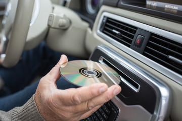 Man playing music in hic car - inserting HI-FI CD into his CD reader slot (shallow DOF)