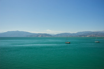 picturesque vivid colorful south sea landscape scenery view with mountain horizon background and two yachts on calm green blue water surface 