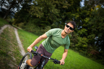 Young man riding his mountain bike outdoors on a forest path