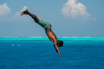 maldivian man diving from boat