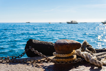 Mooring rope and old bollard on sea water and yachts background