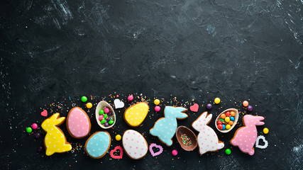 Easter greeting card. Happy Easter. Easter gingerbread cookies and decorative colored eggs. On a black background. Top view. Free copy space.
