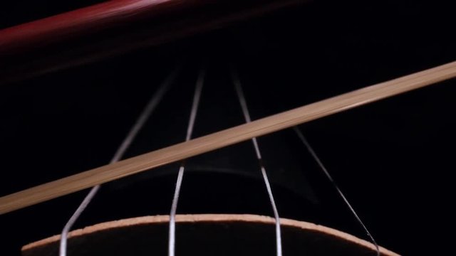 Close-up of the movement of the bow on the strings of a violin