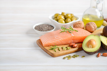 Selection of healthy unsaturated fats, omega 3 - fish, avocado, olives, nuts and seeds.