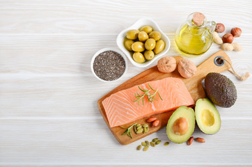 Selection of healthy unsaturated fats, omega 3 - fish, avocado, olives, nuts and seeds.