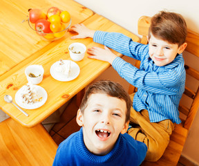 little cute boys eating dessert on wooden kitchen. home interior. smiling adorable friendship...
