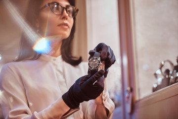 Beautiful woman assistant shows an exclusive men's wristwatch from the new collection in the luxury...