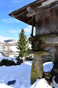Snowy mountain village with galician granary (horreo) and fir tree. Piornedo, Lugo, Spain.