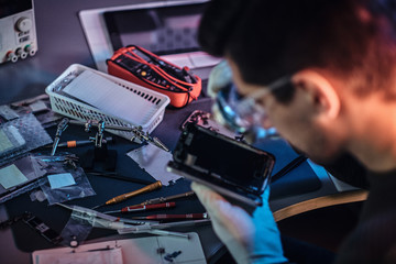 The technician carefully examines the integrity of the internal elements of the smartphone in a modern repair shop