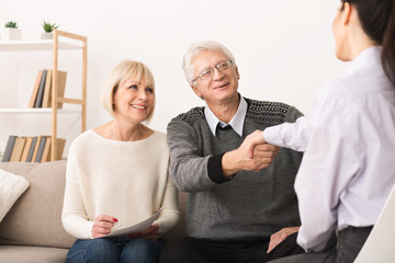Happy senior couple sealing contract with financial advisor
