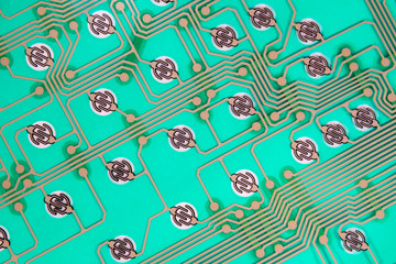 Futuristic looking circuit traces on green. No components, just the traces and contacts. This is from inside a computer keyboard.