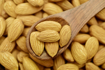 almonds in wooden spoon, background texture
