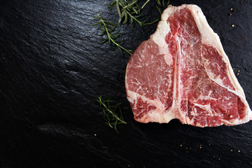 Raw T-bone steak on stone cutting board.