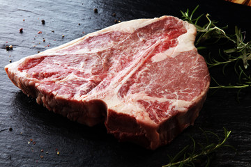 Raw T-bone steak on stone cutting board.