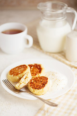 Cottage cheese pancakes with sour cream and tea. Cottage cheese pancakes, syrniki, curd fritters in a white plate. Russian syrniki or sirniki, cottage cheese fritters.