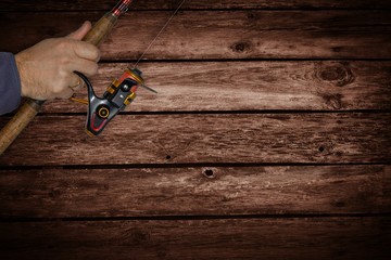 fishing background, wooden planks and hand holding a fishing rod
