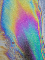 Multi colored oil spill on asphalt road, abstract background,