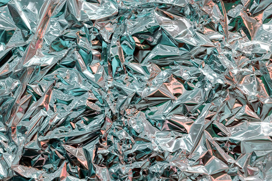 Holographic texture wrinkled metal foil. Hologram abstract 80s style background with blue, purple and silver colors. Texture of kaleidoscope, webpunk and vaporwave concept