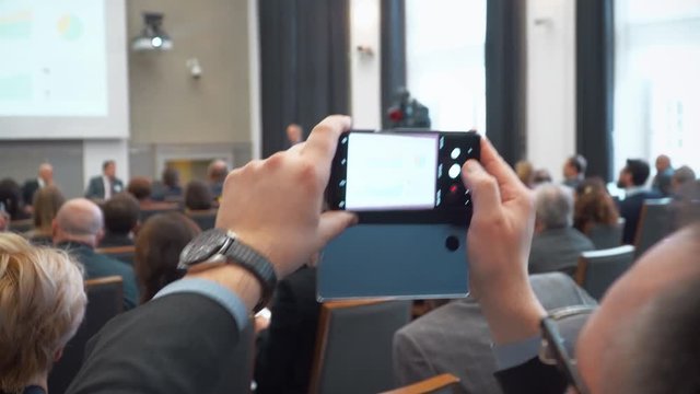 man takes a photo during a conference