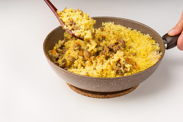 Frying pan full of yellow rice minced meat on white