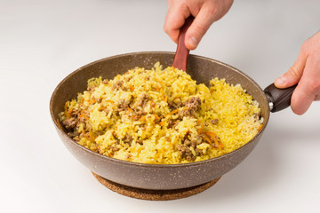 Frying pan full of yellow rice miced meat on white