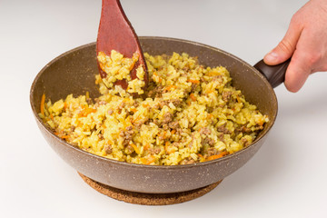 Frying pan full of yellow rice minced meat on white